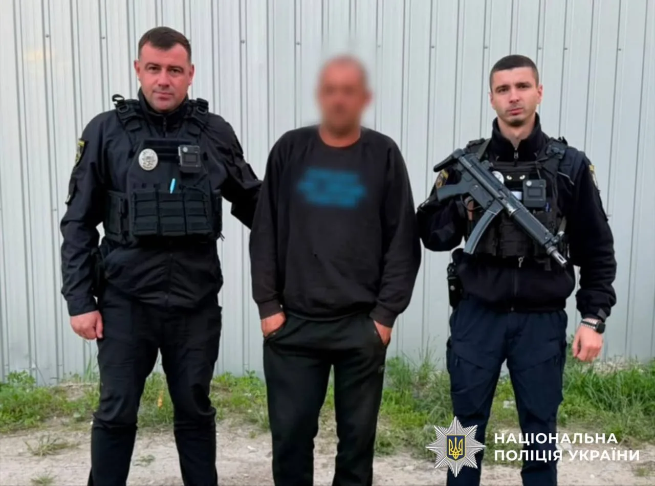 Двоє поліцейських з затриманою особою біля будівлі