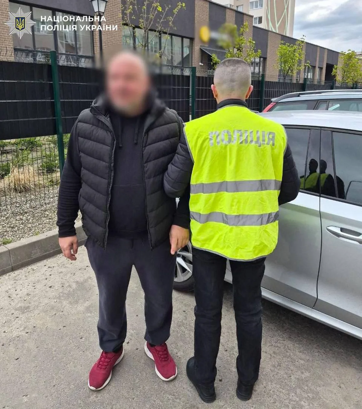 Поліцейський у жилеті супроводжує затриманого чоловіка