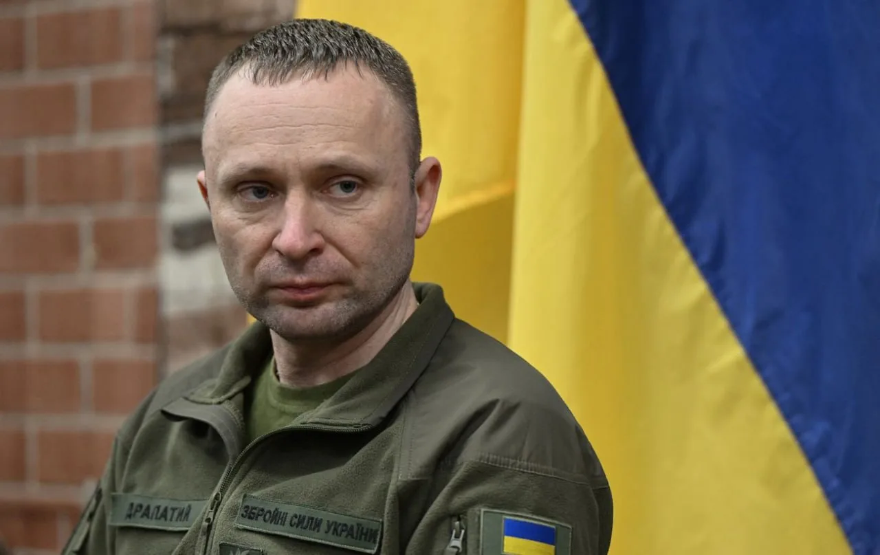 Чоловік у військовій формі на тлі українського прапора