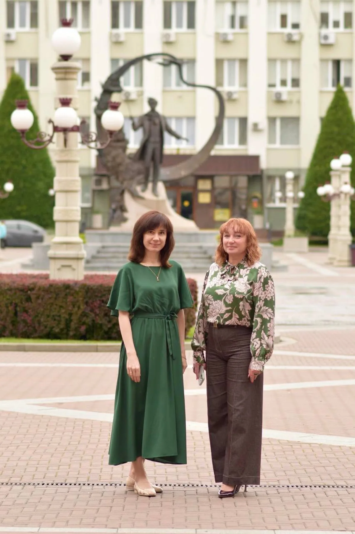 Дві жінки стоять на площі біля пам'ятника
