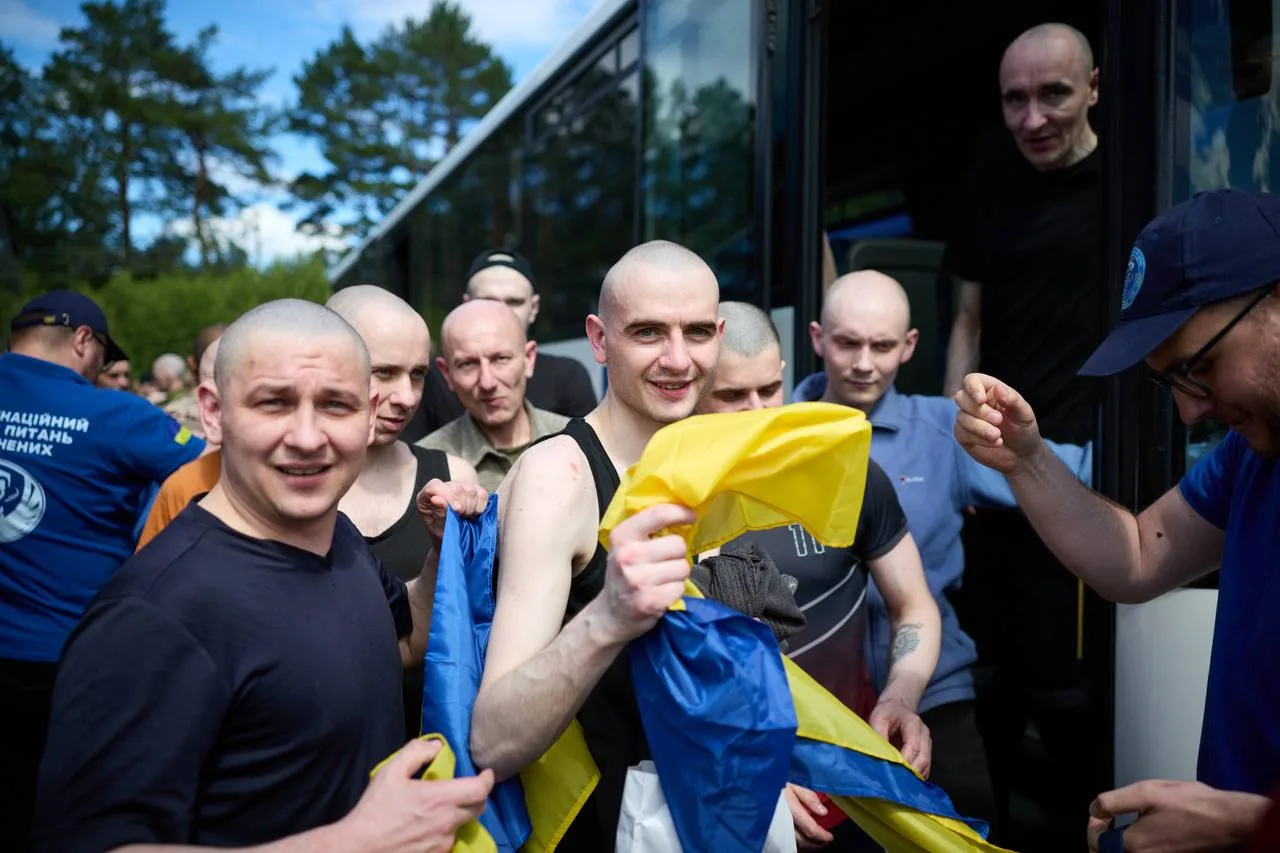 Група звільнених українських військовослужбовців біля автобуса
