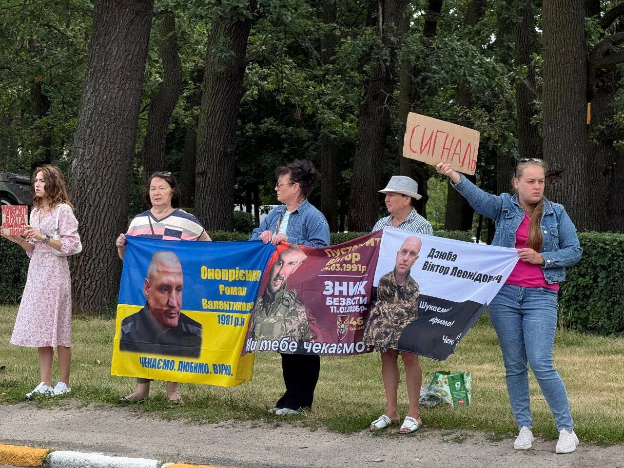 Група людей на вулиці з плакатами та прапорами на підтримку військовополонених