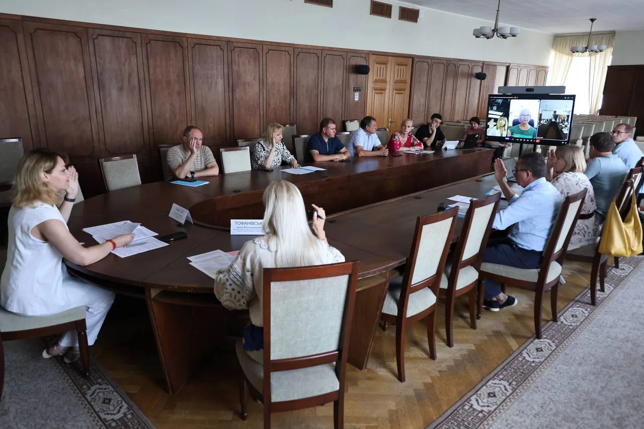 Засідання в залі з дерев'яною обшивкою, люди за столом