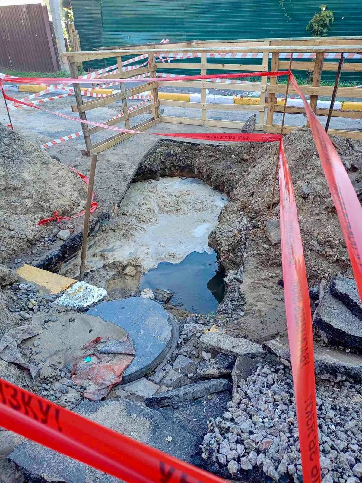 Вирва на дорозі з пошкодженим водопровідним трубопроводом