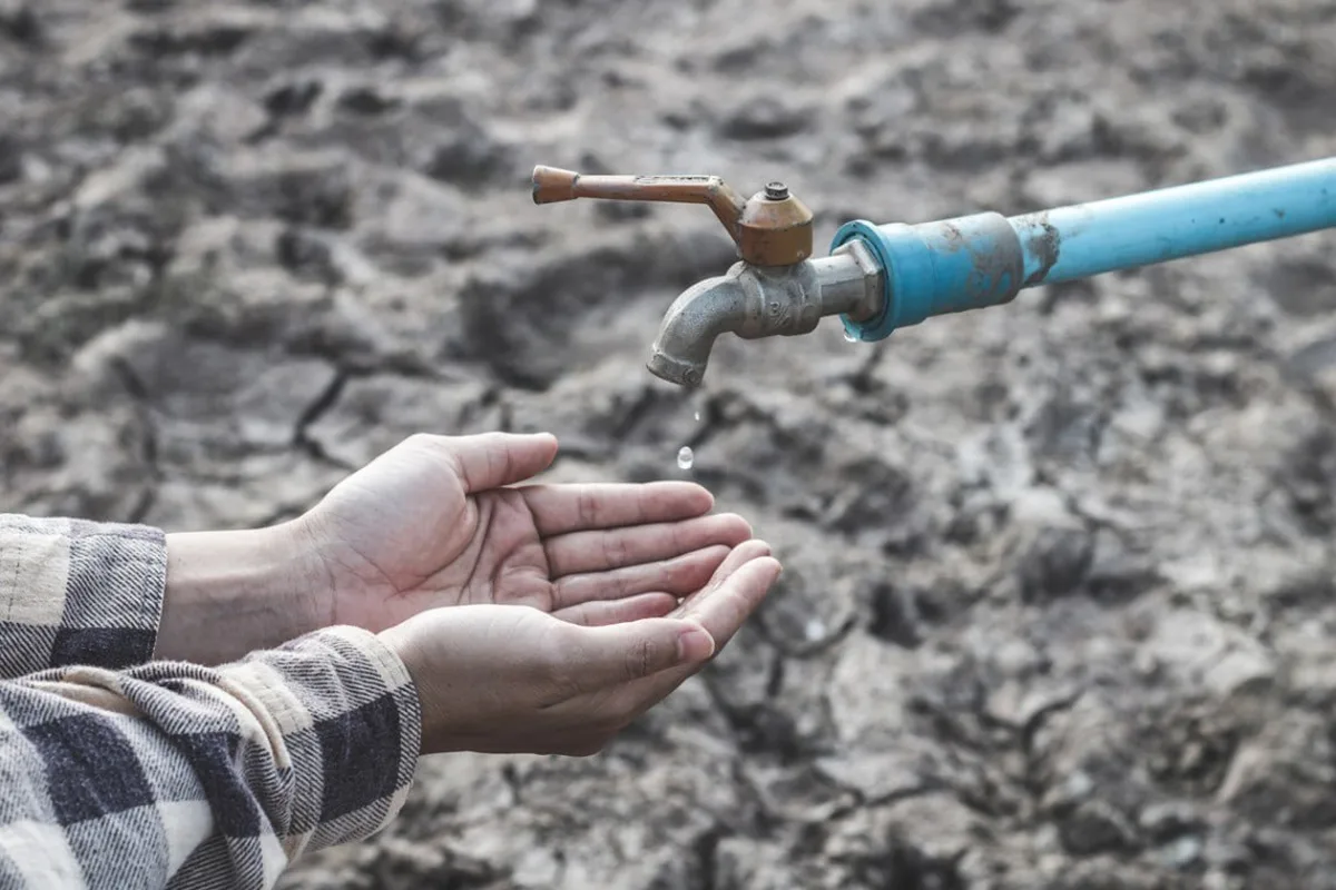 Руки під краном з водою на сухому ґрунті