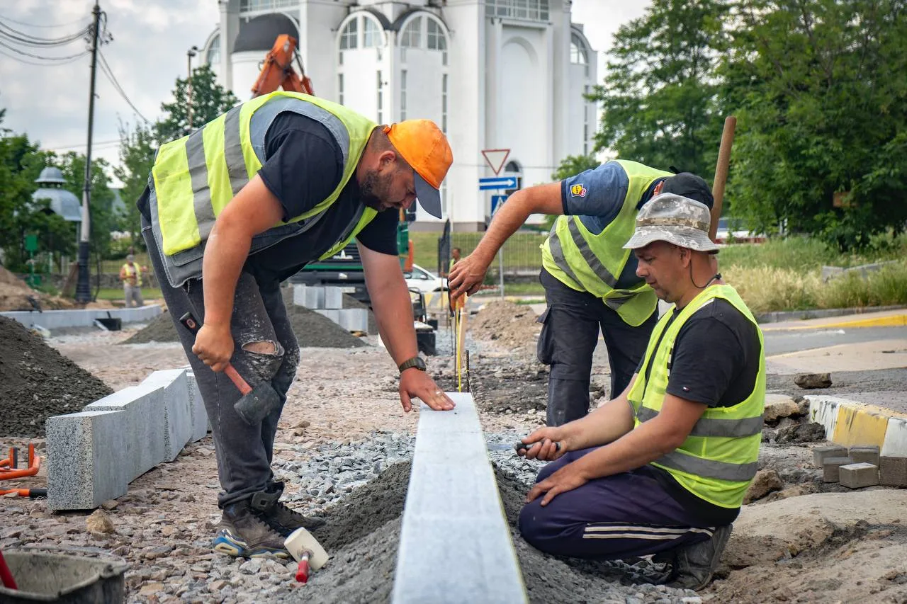 Робітники в жилетах укладають бордюр на вулиці