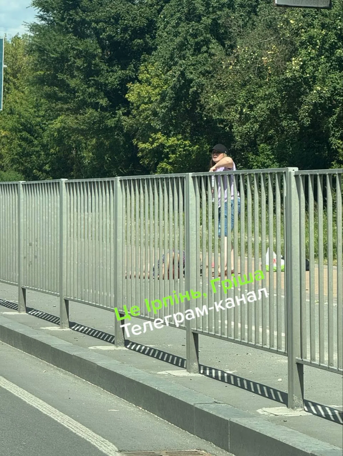 Жінка стоїть біля металевого паркану на мосту