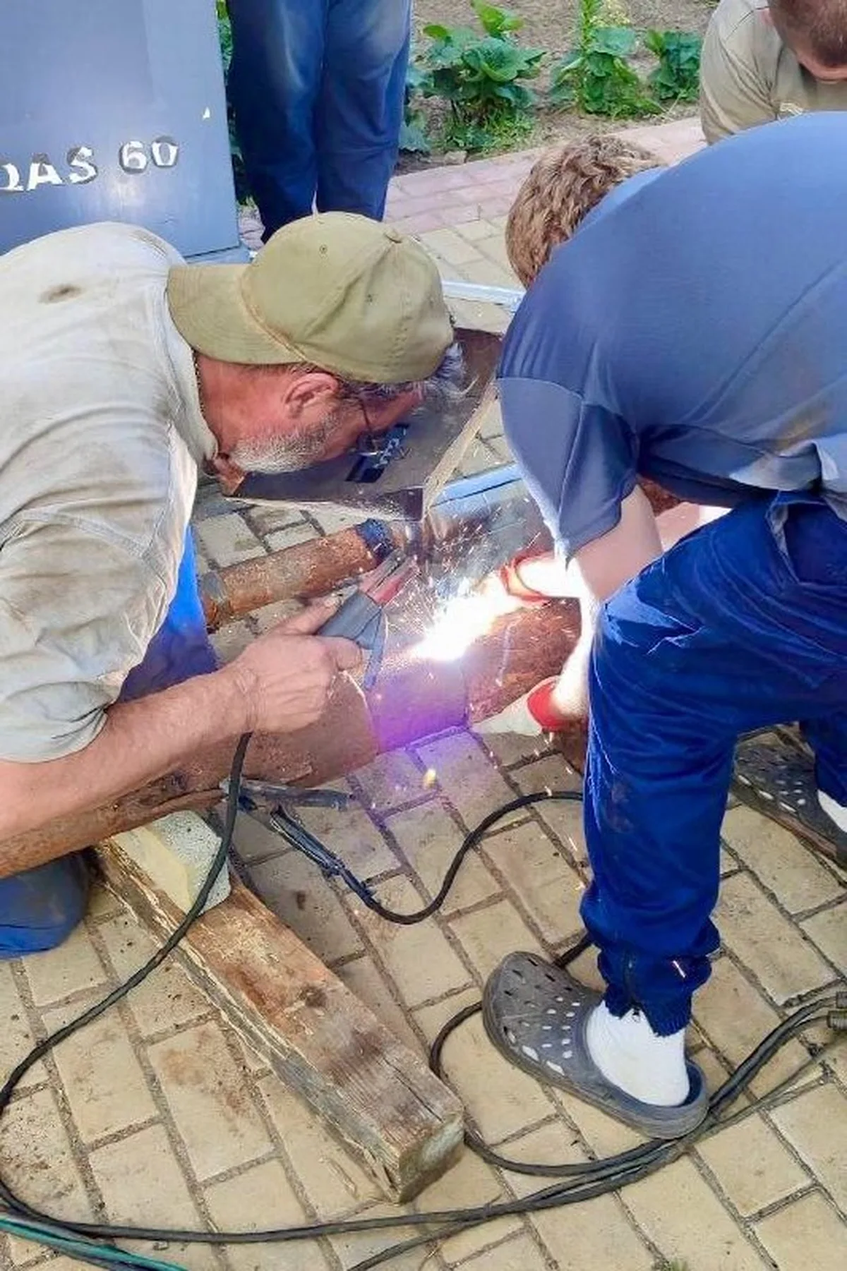Чоловік зварює металеву конструкцію на вулиці