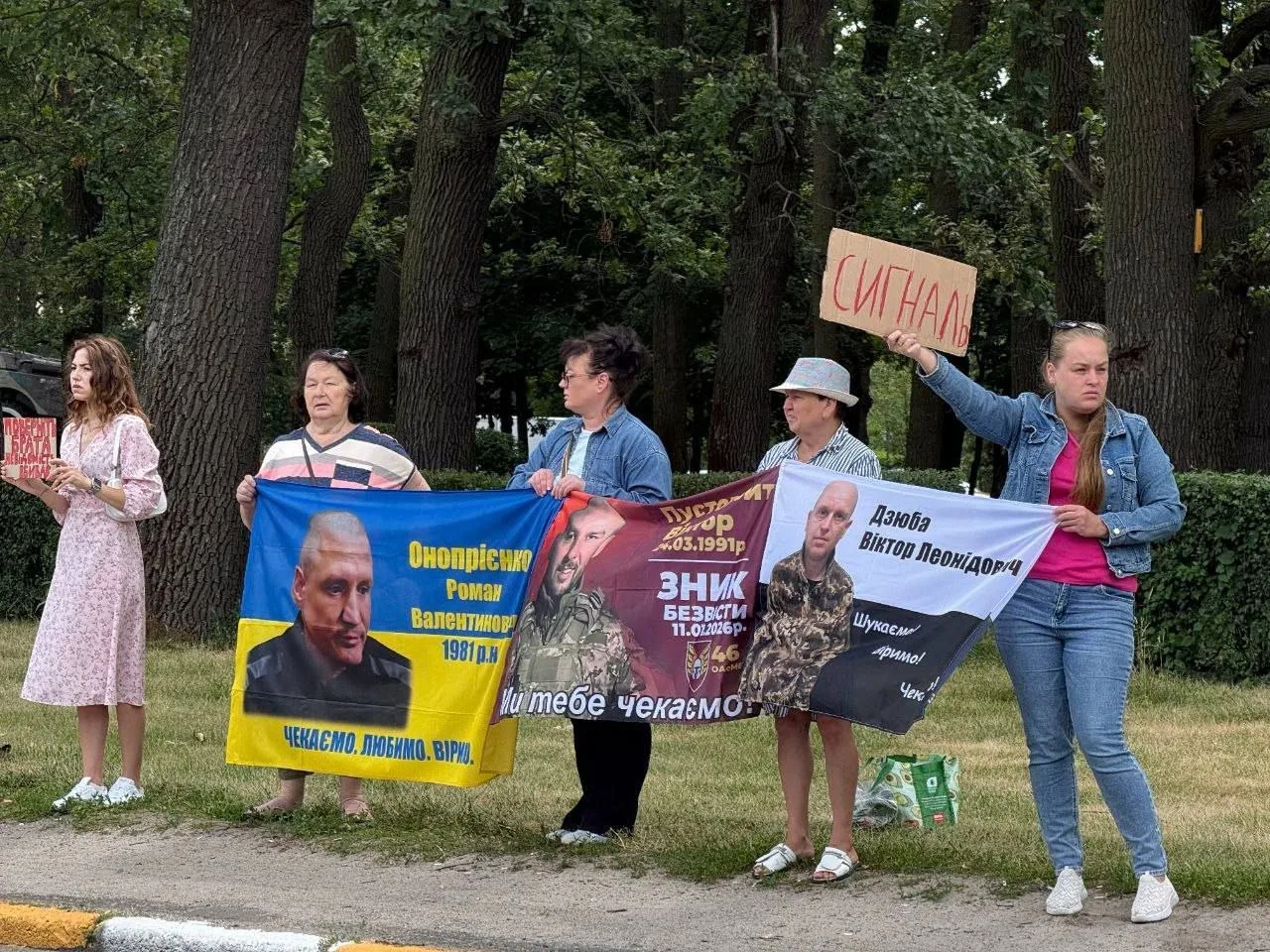 Група людей з плакатами та прапорами на мирній акції в парку