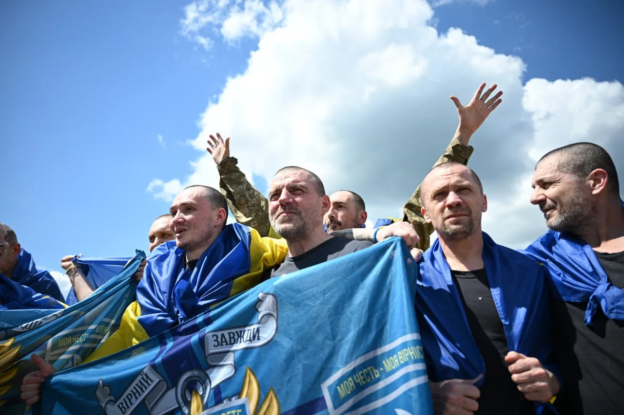 Група чоловіків з українськими прапорами піднімає руки