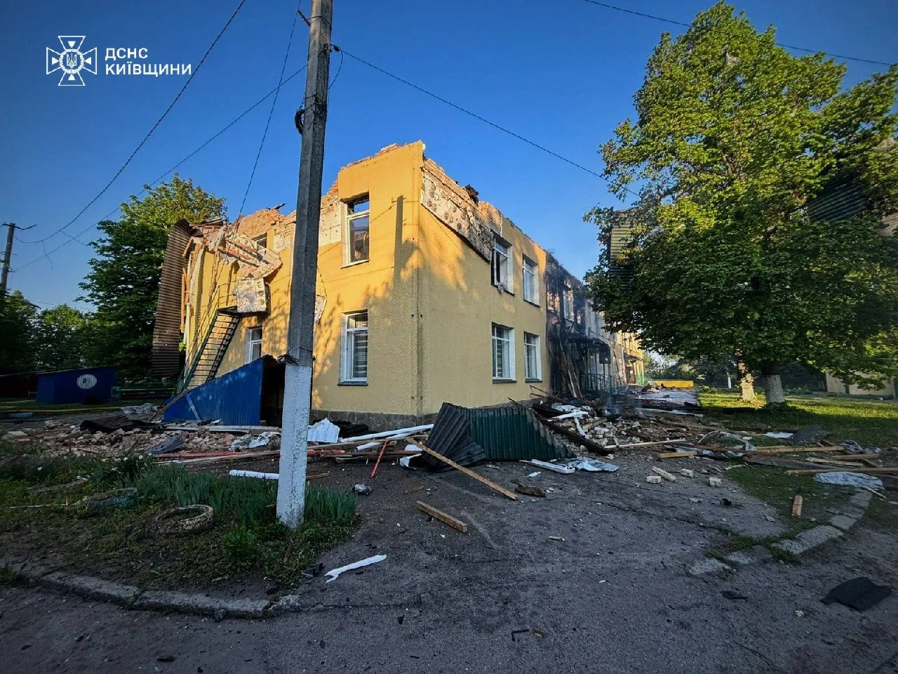 Пошкоджена жовта житлова будівля з вибитими вікнами