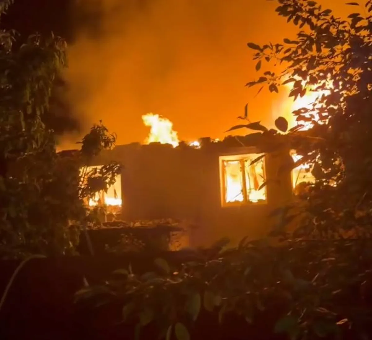 Будинок охоплений вогнем вночі, видно палаючі вікна
