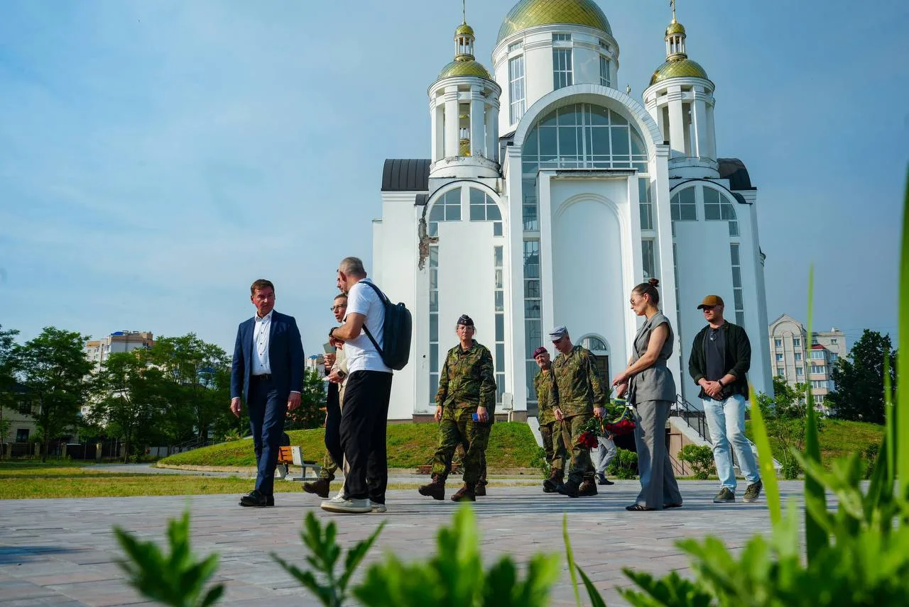 Група людей стоїть перед білою церквою з золотими куполами