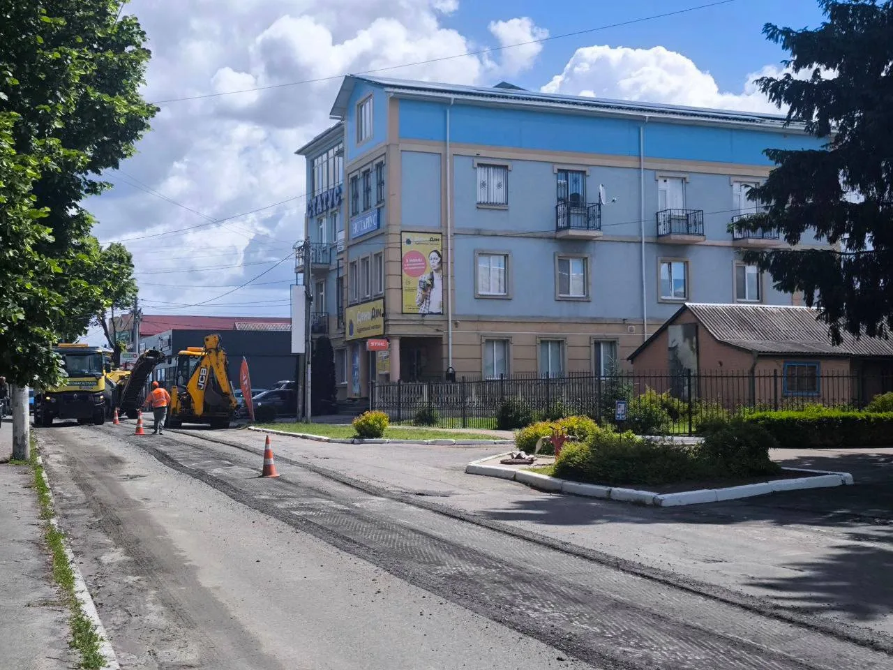 Робітники ремонтують дорогу біля чотирьохповерхової будівлі