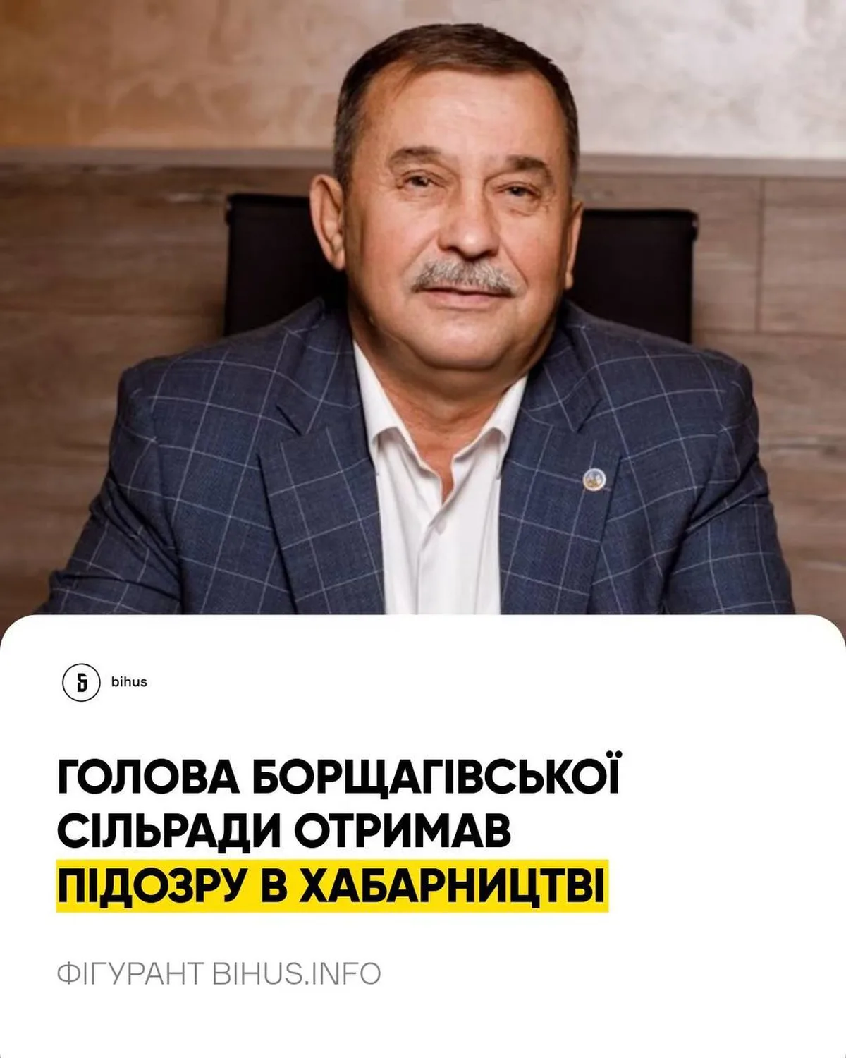 Чоловік у темному піджаку сидить в офісі