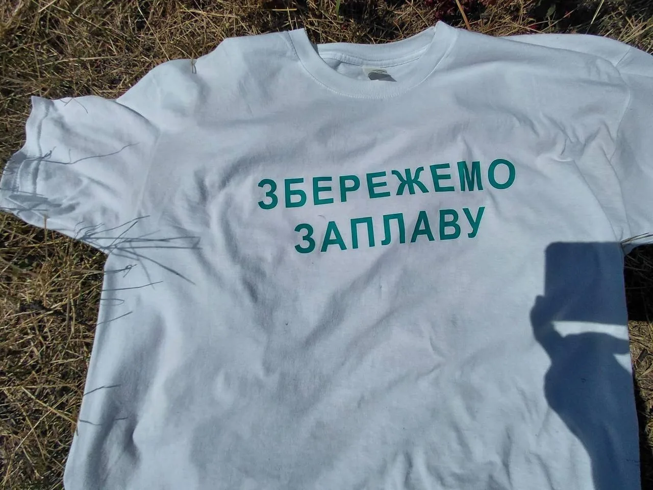 Біла футболка з написом про збереження заплави річки