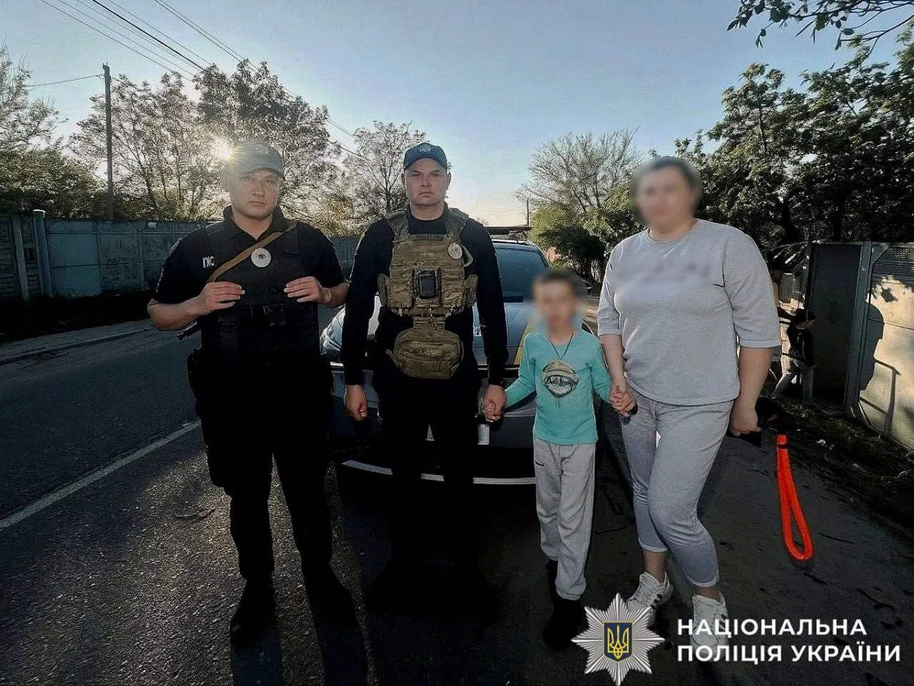 Поліцейські з дитиною та жінкою на вулиці села