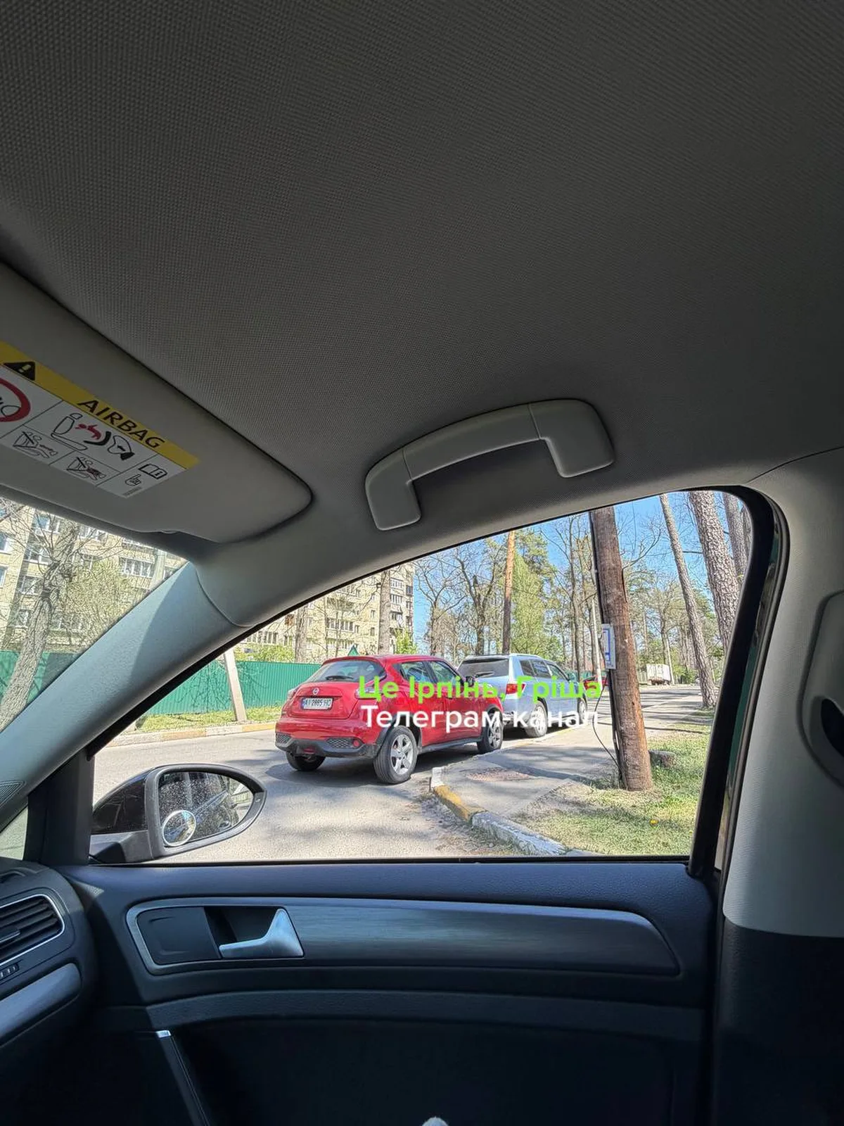 Вид з салону автомобіля на припаркований червоний автомобіль