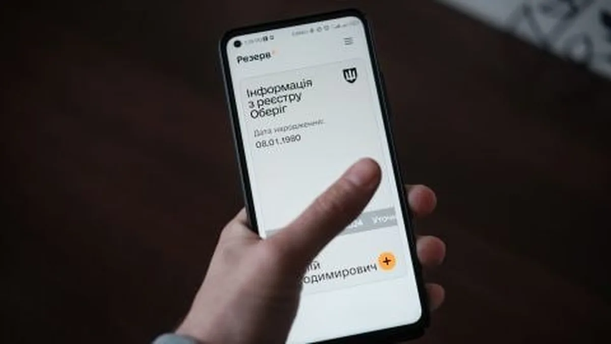 Рука тримає смартфон з інформацією про Обереги