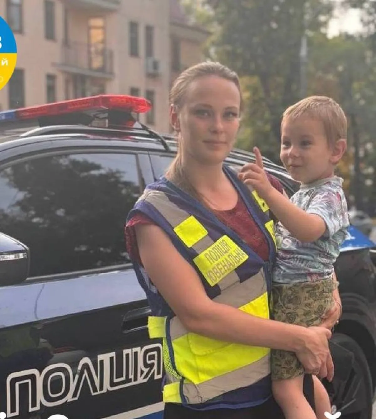 Поліцейська з дитиною біля патрульного автомобіля