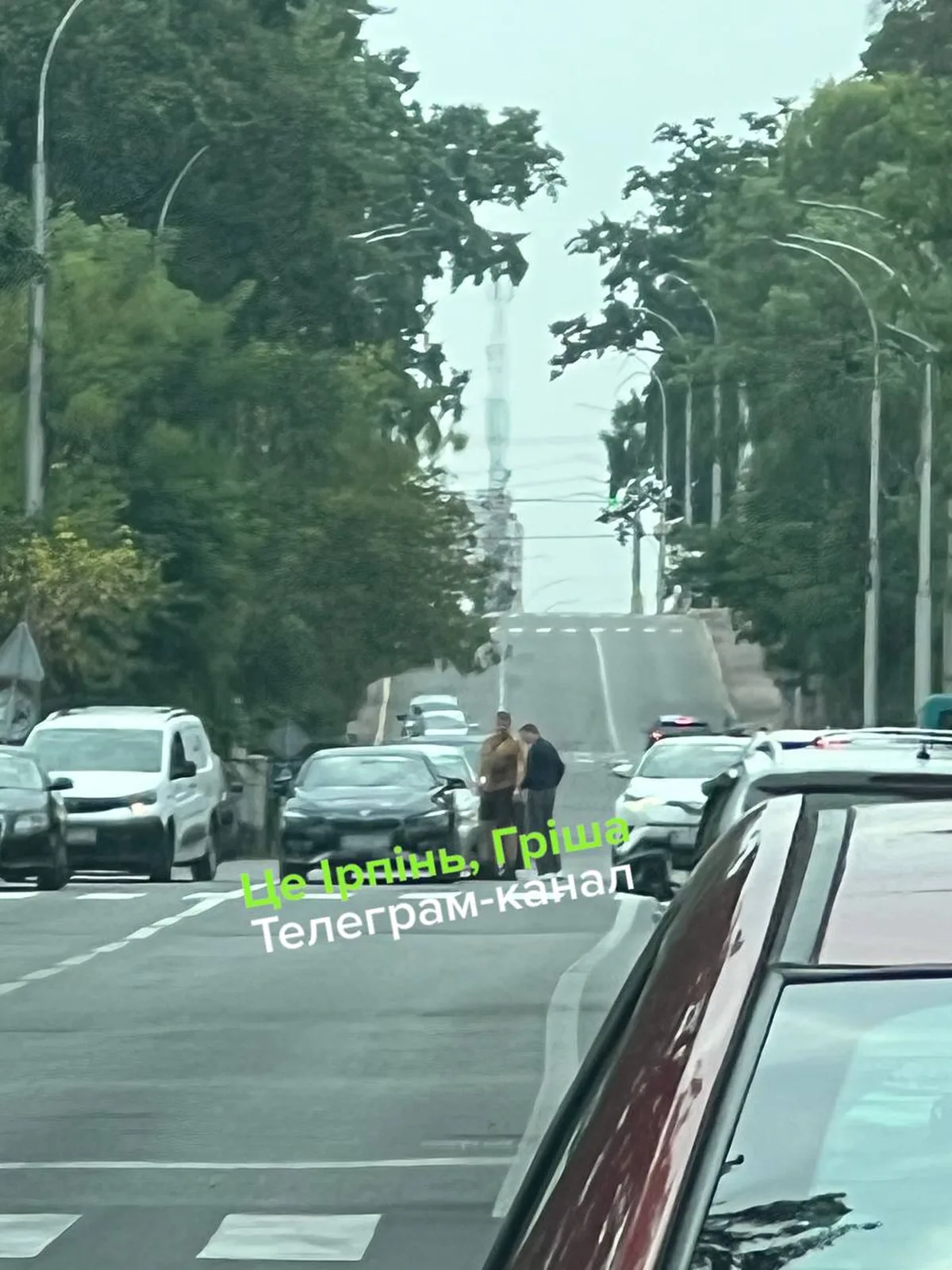 Вулиця з припаркованими автомобілями та людьми біля дороги