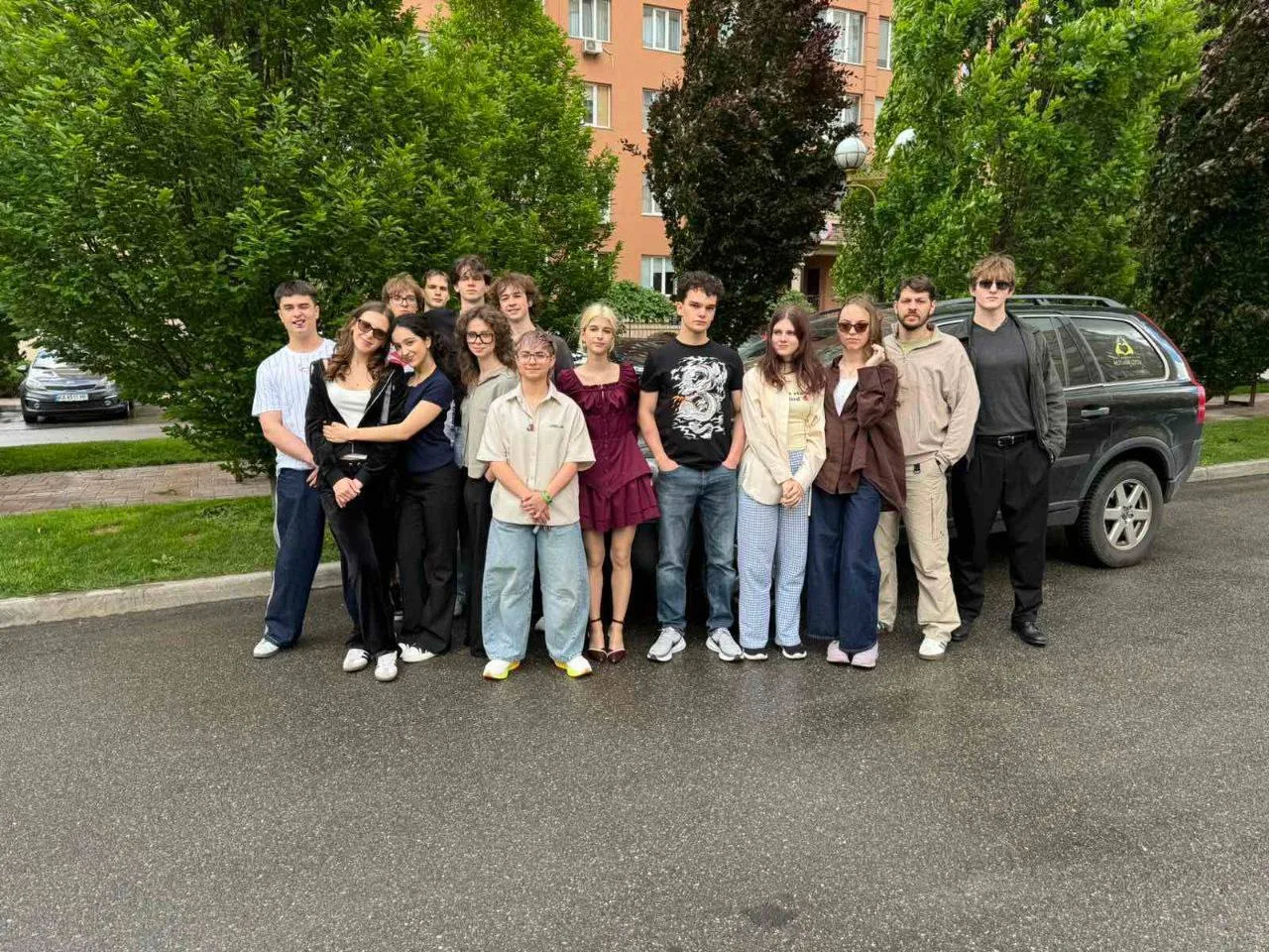 Група людей стоїть на дорозі біля автомобіля