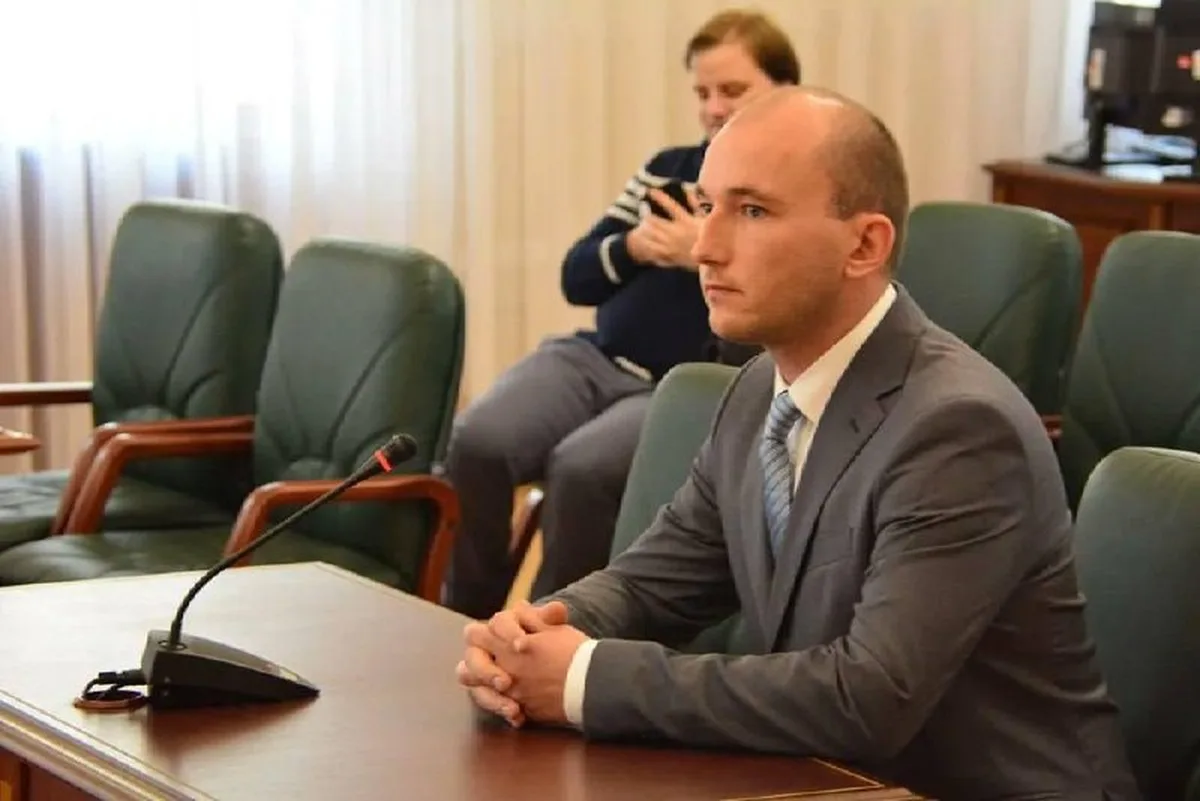 Чоловік у костюмі сидить за столом на засіданні