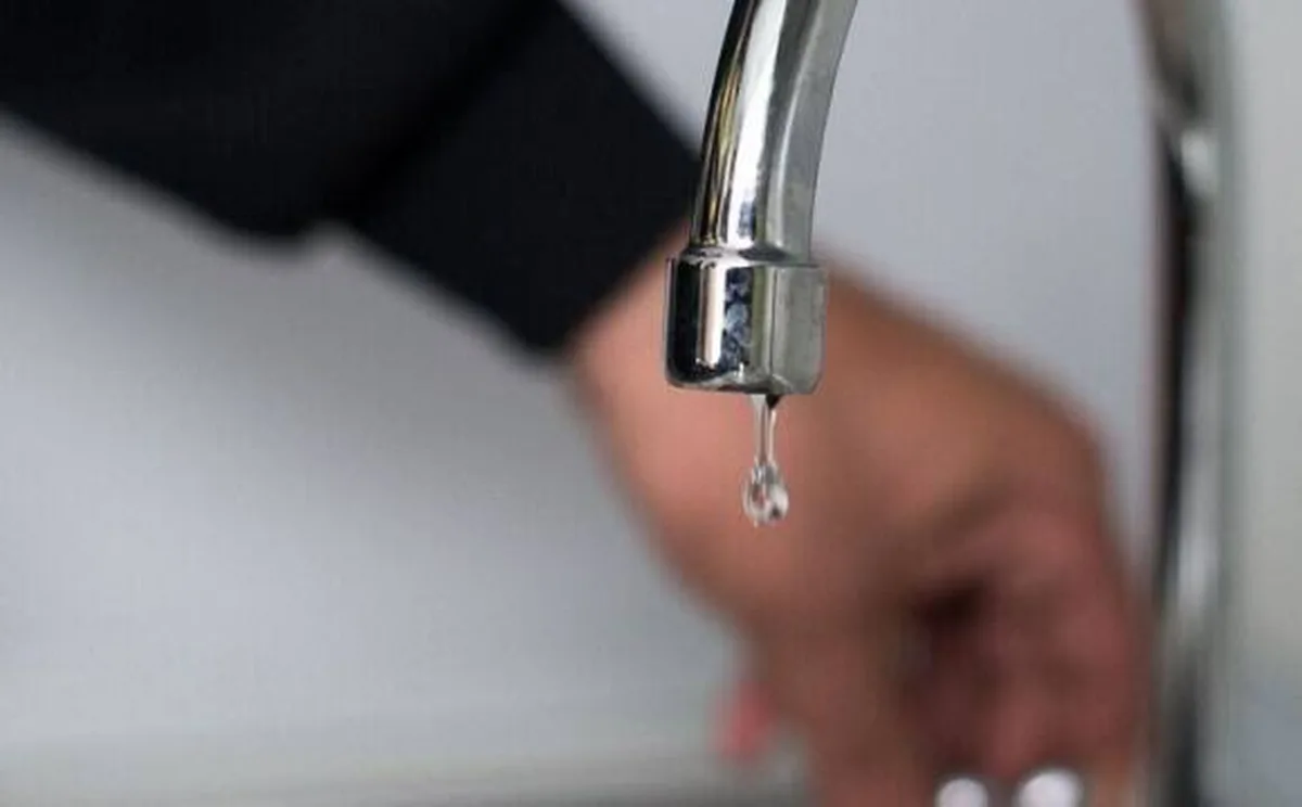 Крапля води падає з крана під рукою