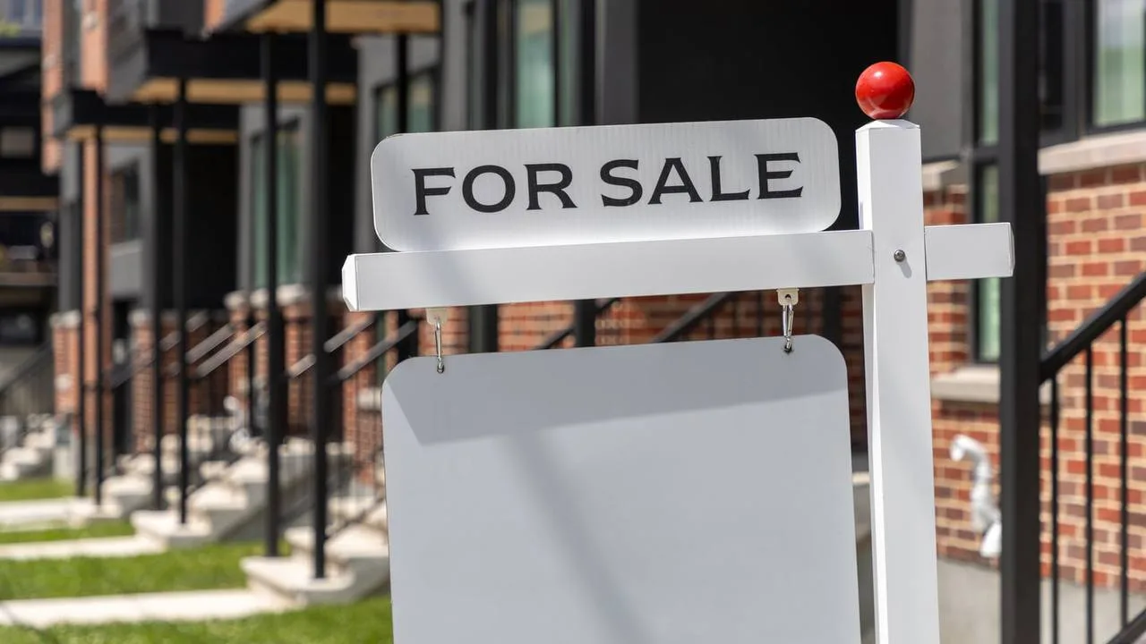 Табличка "FOR SALE" біля цегляної будівлі