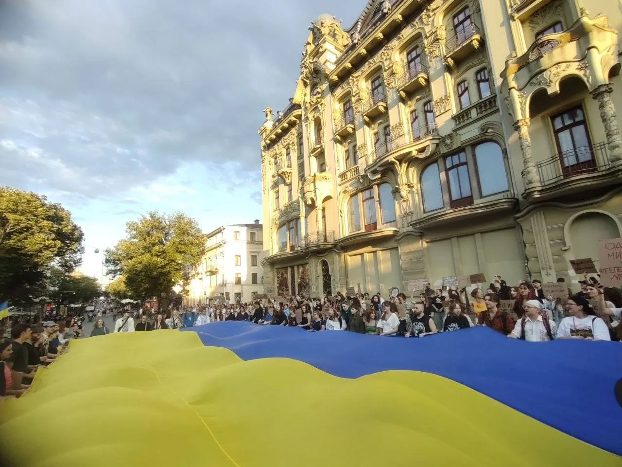 Люди тримають великий український прапор на вулиці