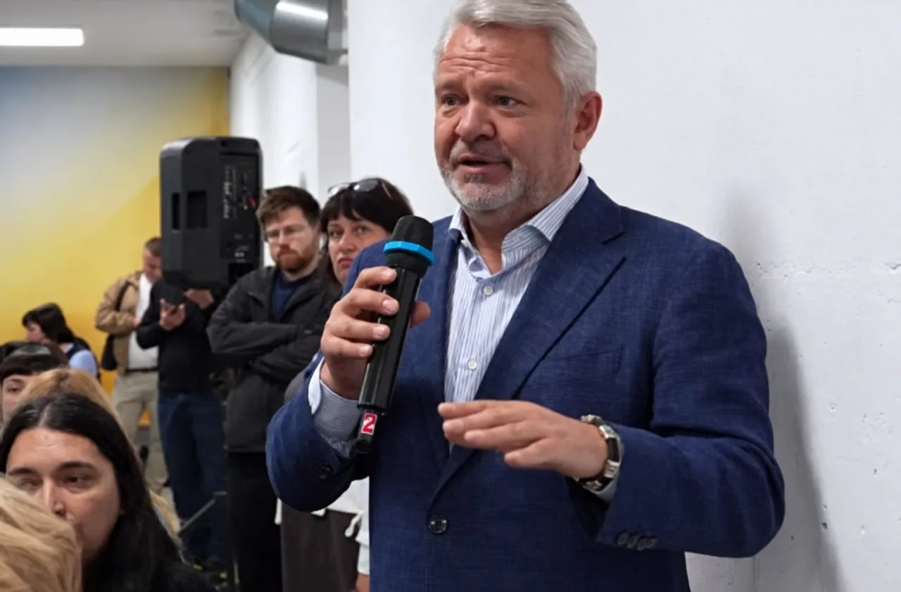 Чоловік у темному піджаку говорить у мікрофон перед аудиторією