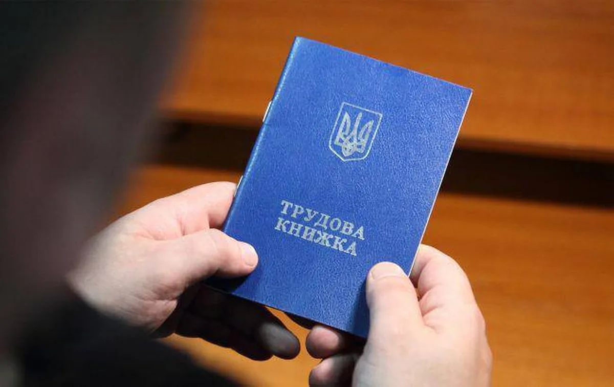 Руки тримають синю трудову книжку з гербом України