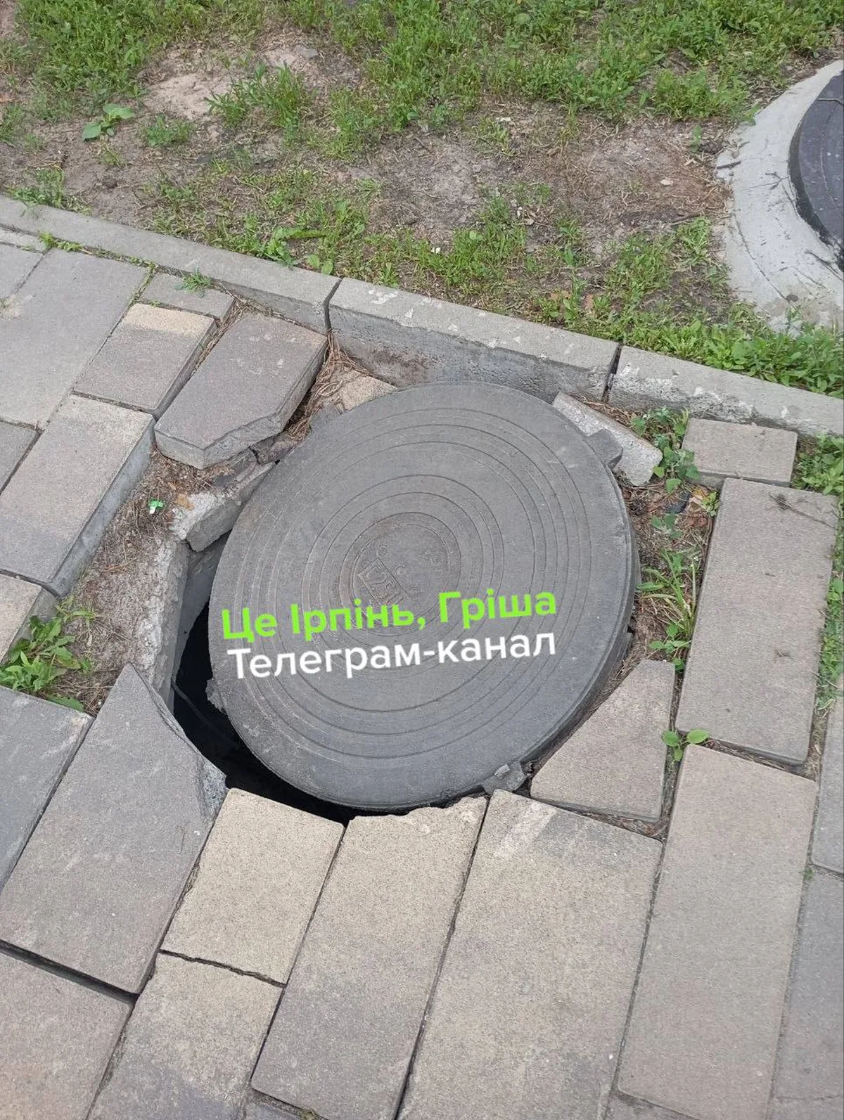 Відкритий люк каналізації на тротуарі парку
