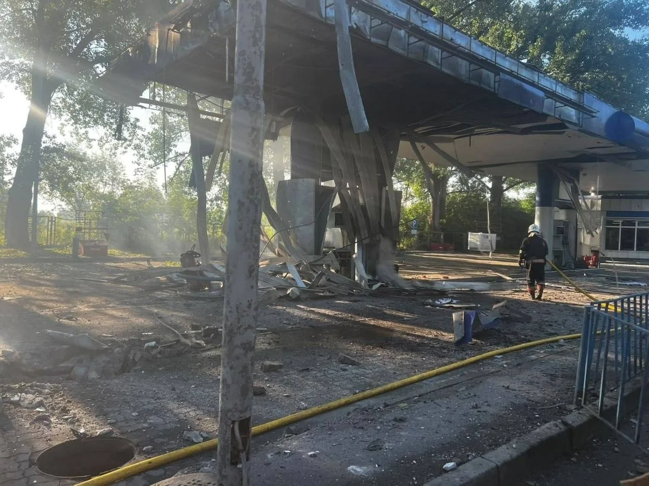 Пошкоджена автозаправна станція під мостом, жовта стрічка огородження
