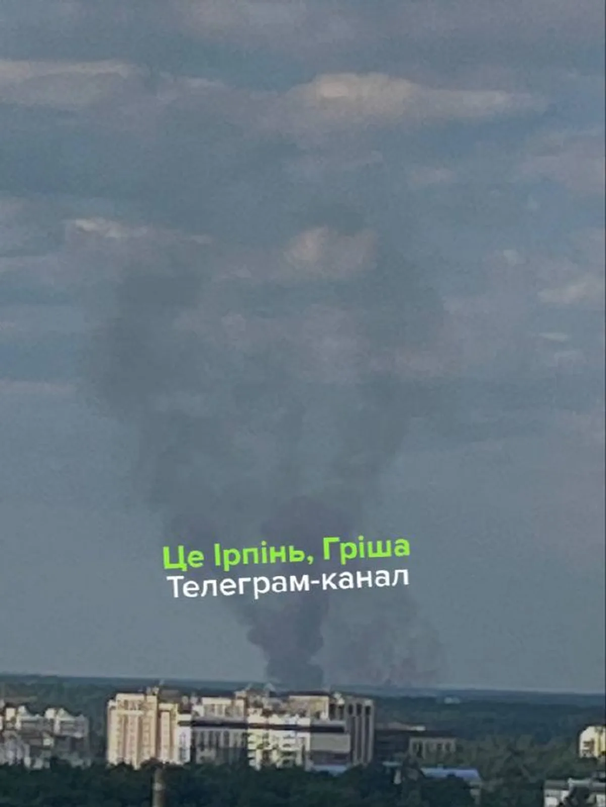 Великий стовп диму над містом у денний час