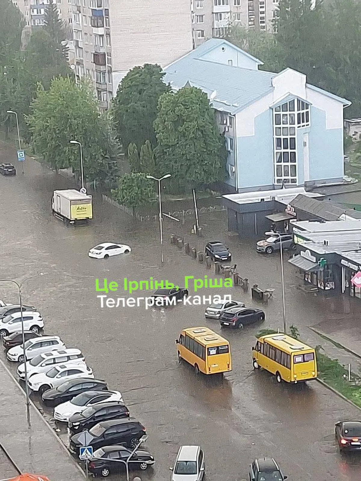 Затоплена вулиця з припаркованими автомобілями та жовтими маршрутками
