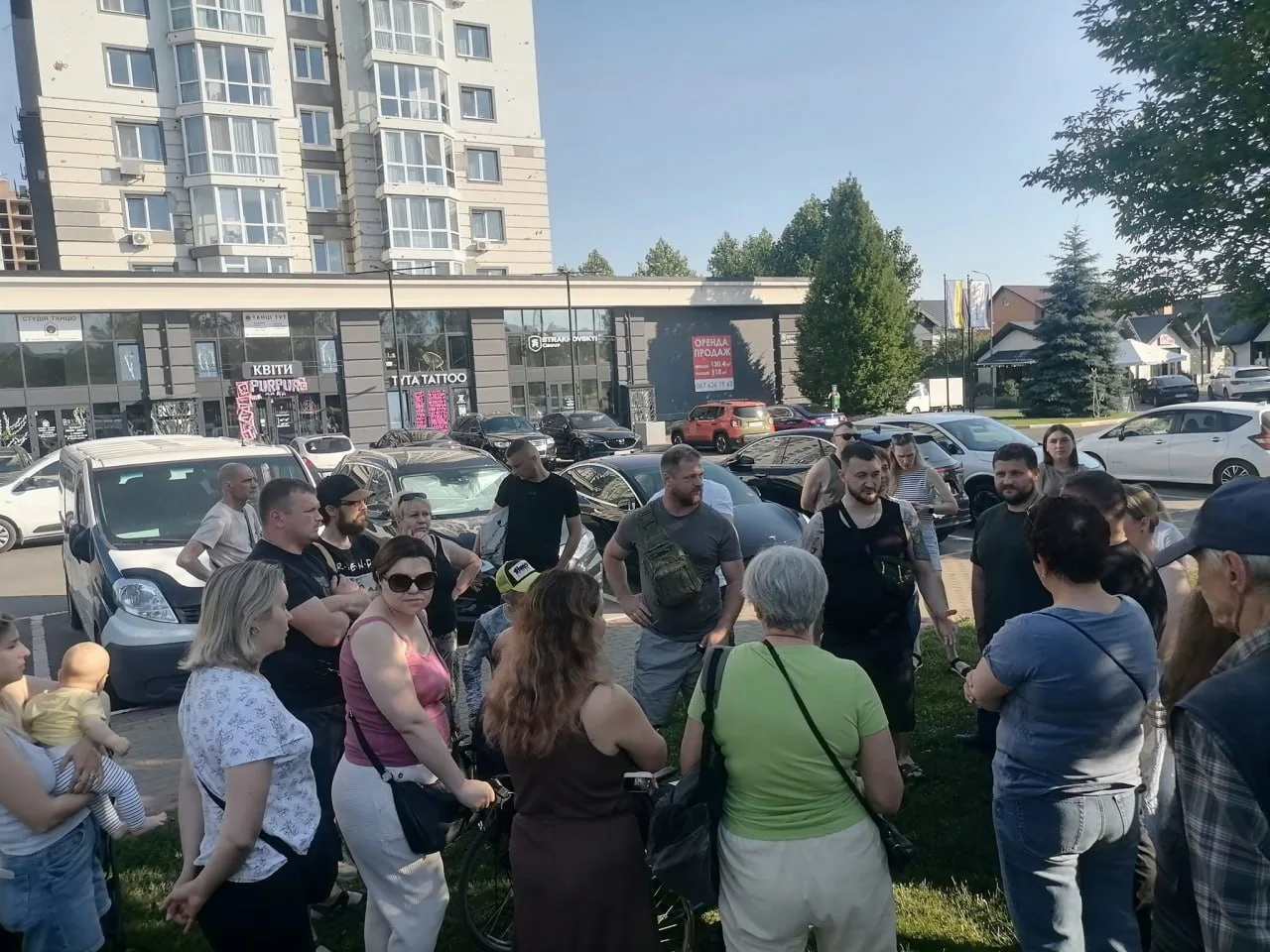 Група людей на зібранні біля припаркованих автомобілів