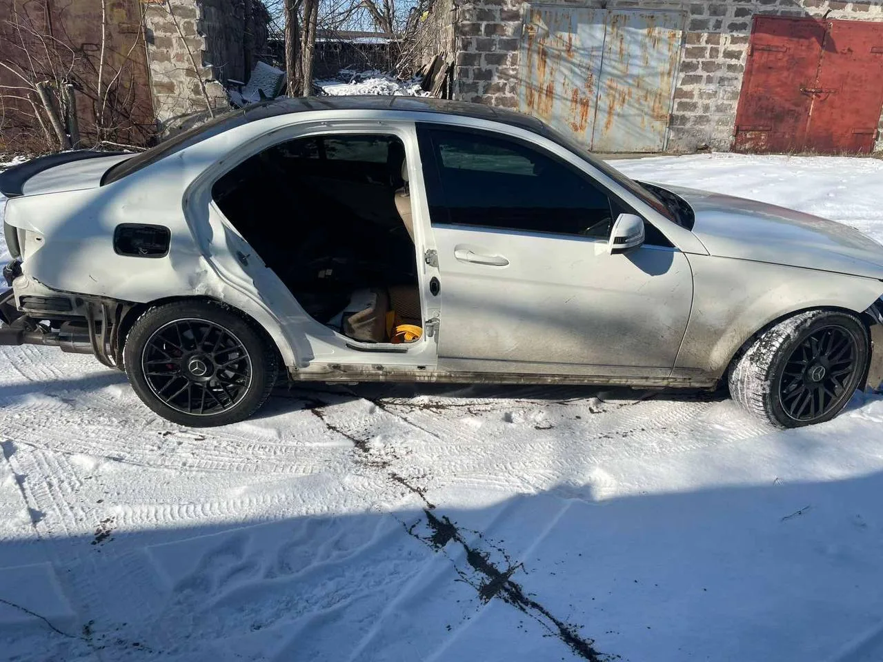 Пошкоджений автомобіль сірого кольору на снігу