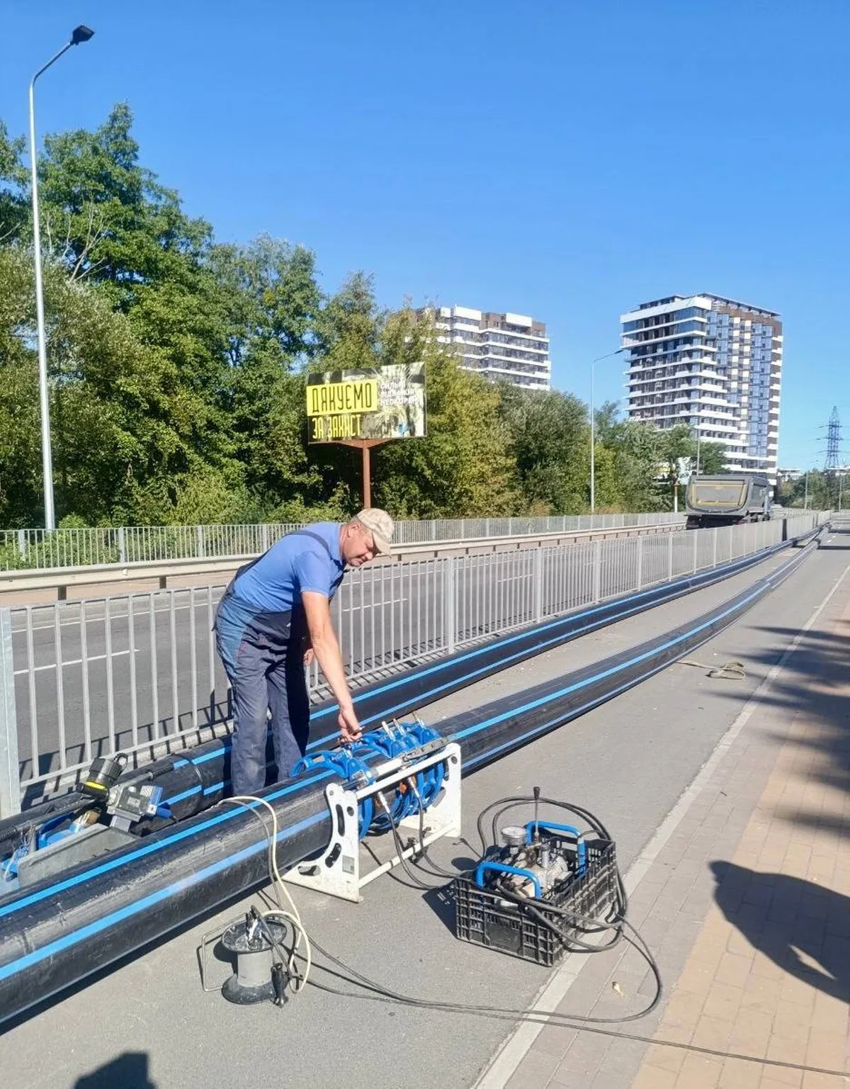 Робітник чистить каналізаційну трубу на мосту