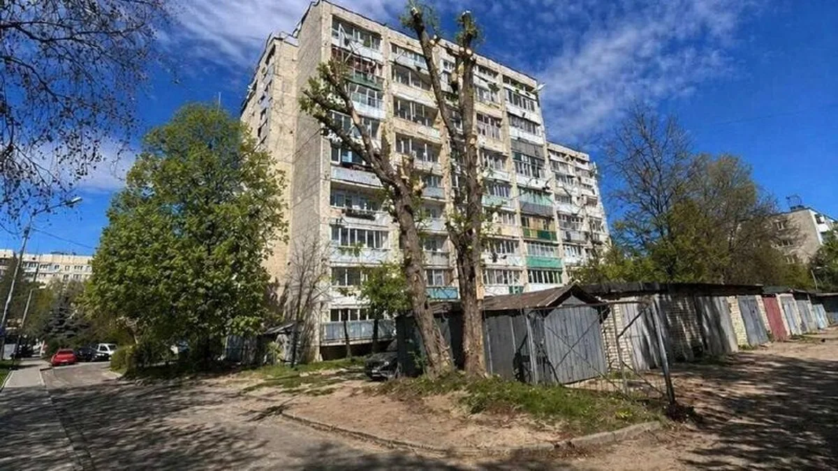 Багатоповерховий житловий будинок з пошкодженнями та металевим парканом
