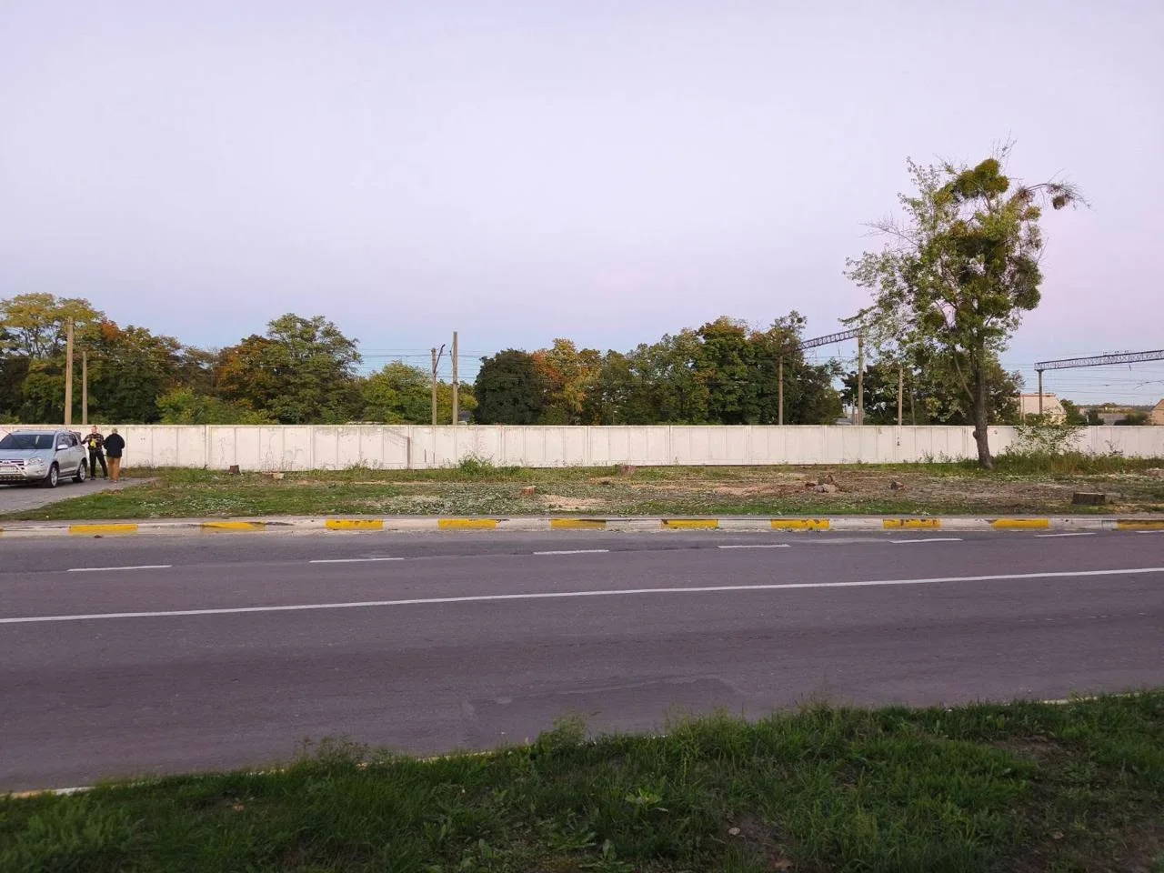 Асфальтована дорога біля білого паркану та дерев