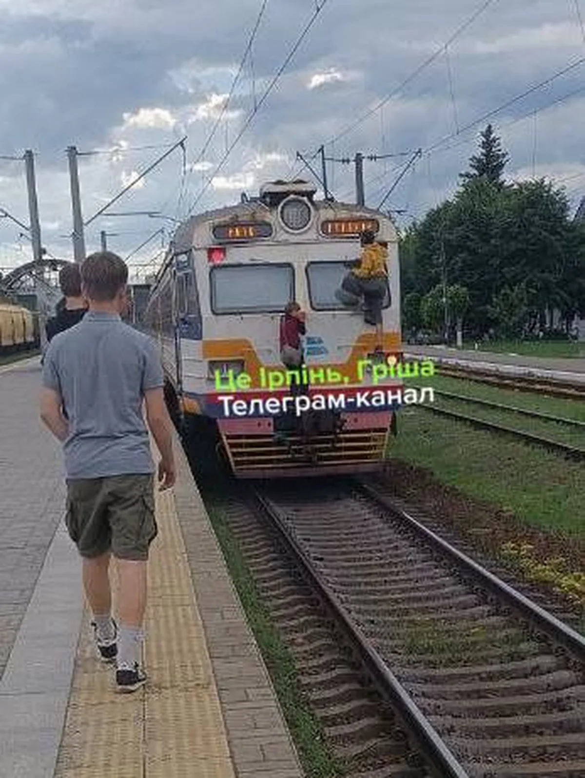 Хлопчик біля залізничної колії та електропоїзда на станції