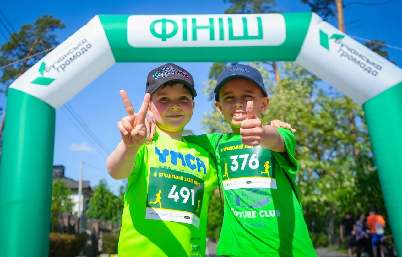 Два учасники в зелених футболках на фінішу забігу