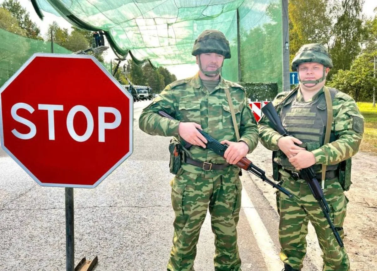 Двоє військовослужбавців у камуфляжі біля знака STOP на блокпості