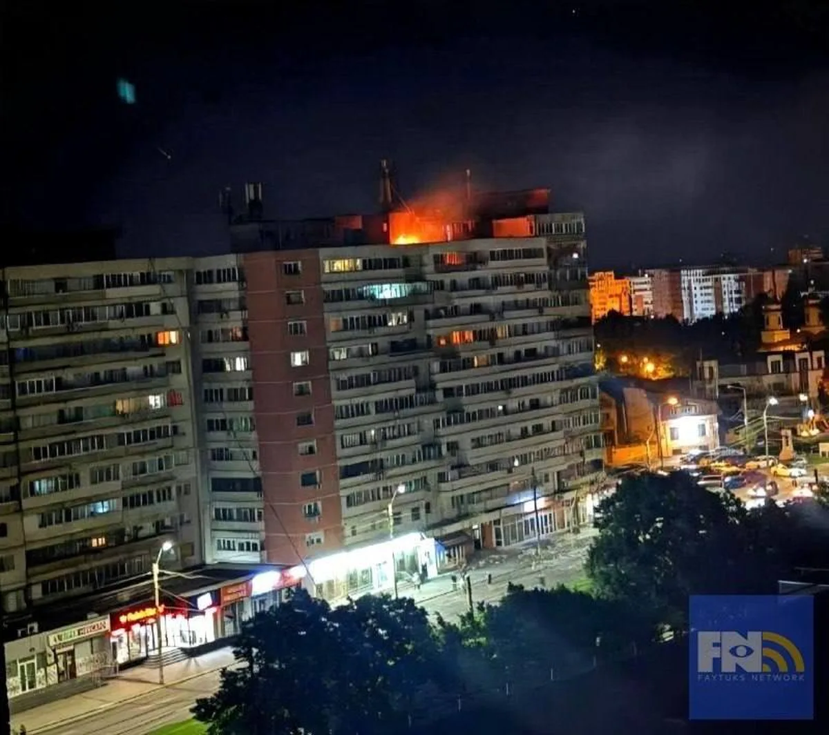 Пошкоджена будівля з вогнем на даху вночі