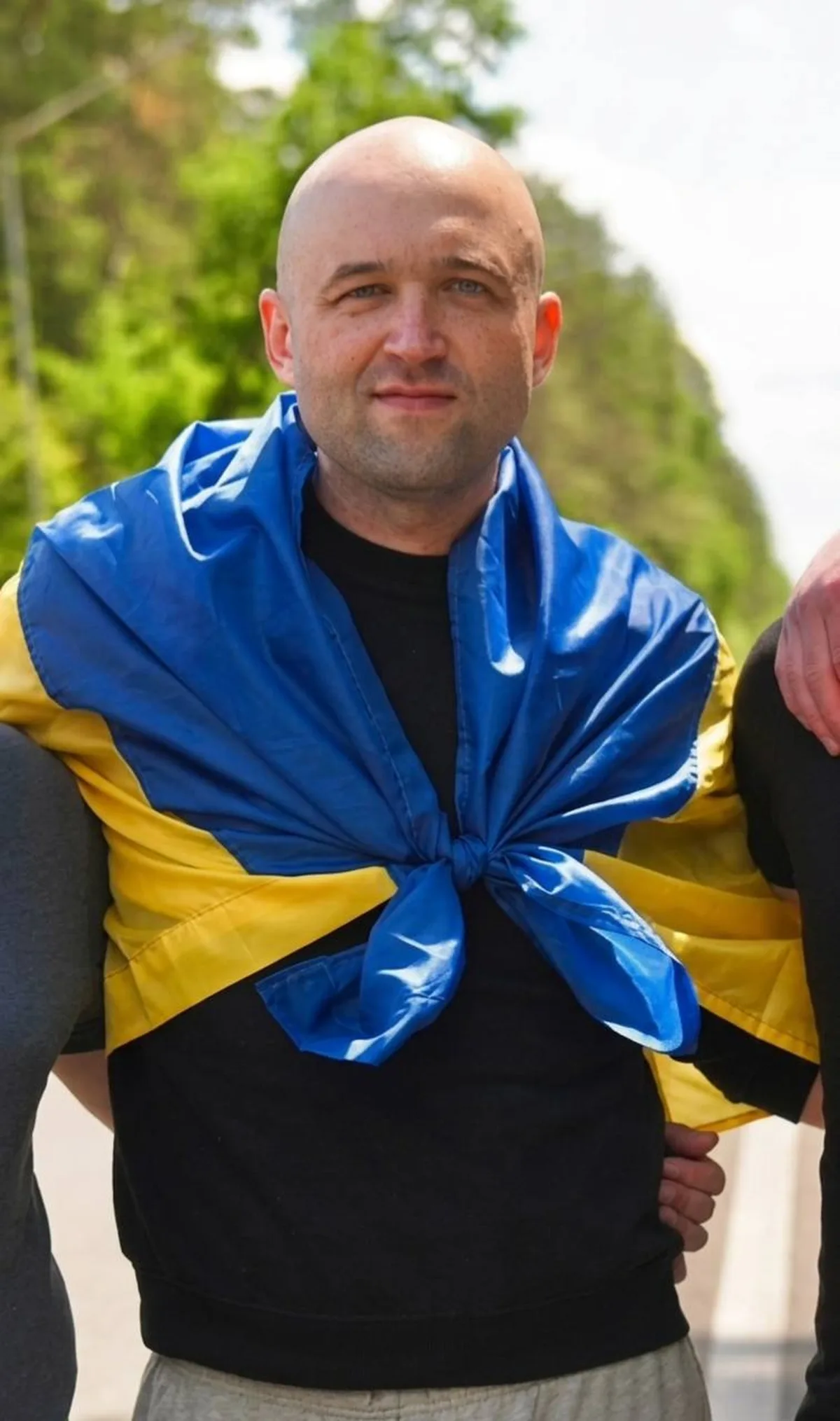 Чоловік з синьо-жовтою стрічкою на плечах на вулиці