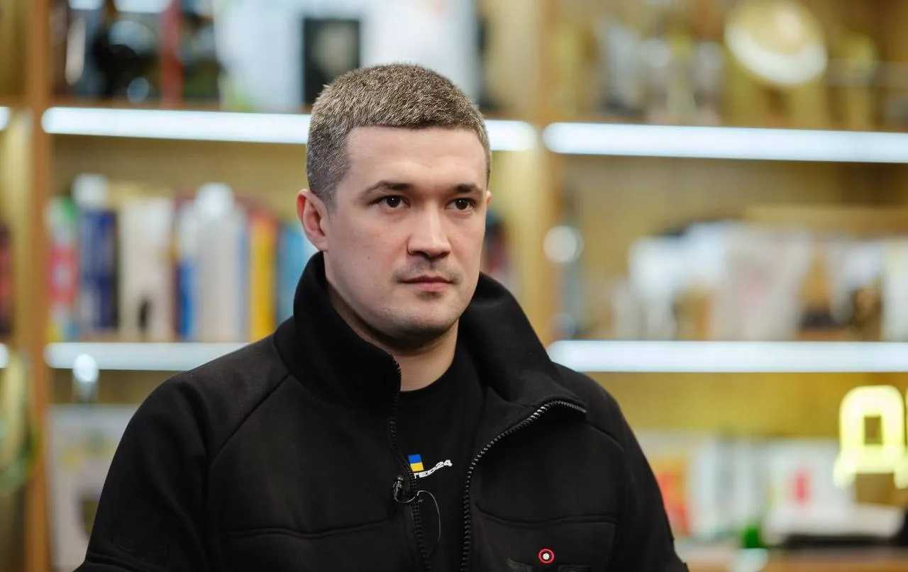 Чоловік у чорній куртці в інтер'єрі з книжками