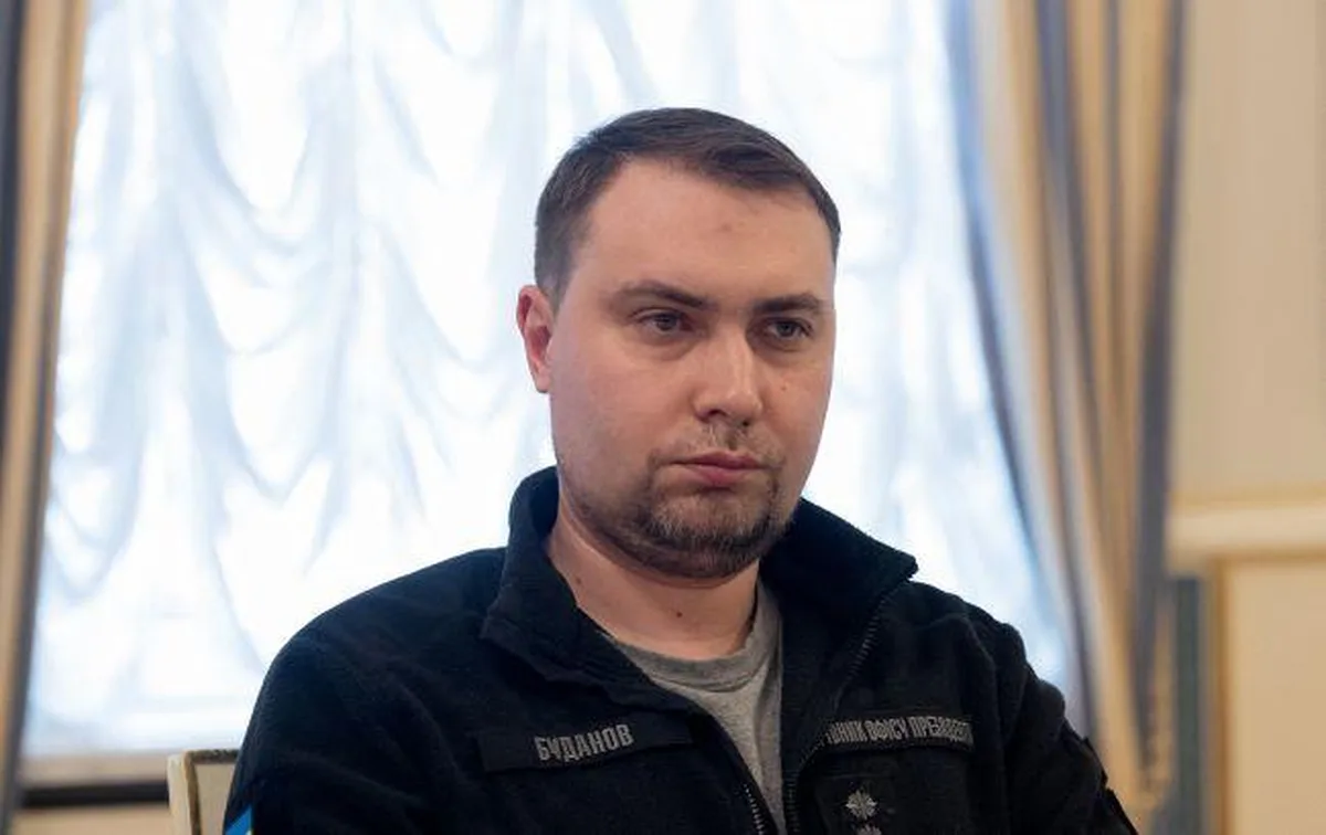 Чоловік у чорній куртці на фоні вікна з завісками