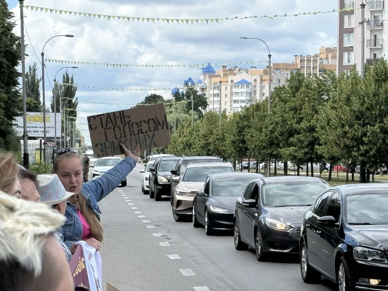 Люди з плакатом на вулиці під час автомобільної акції