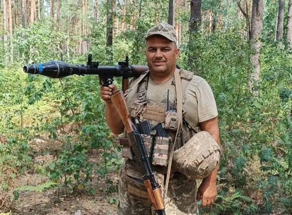 Чоловік у військовому спорядженні в лісі з зброєю